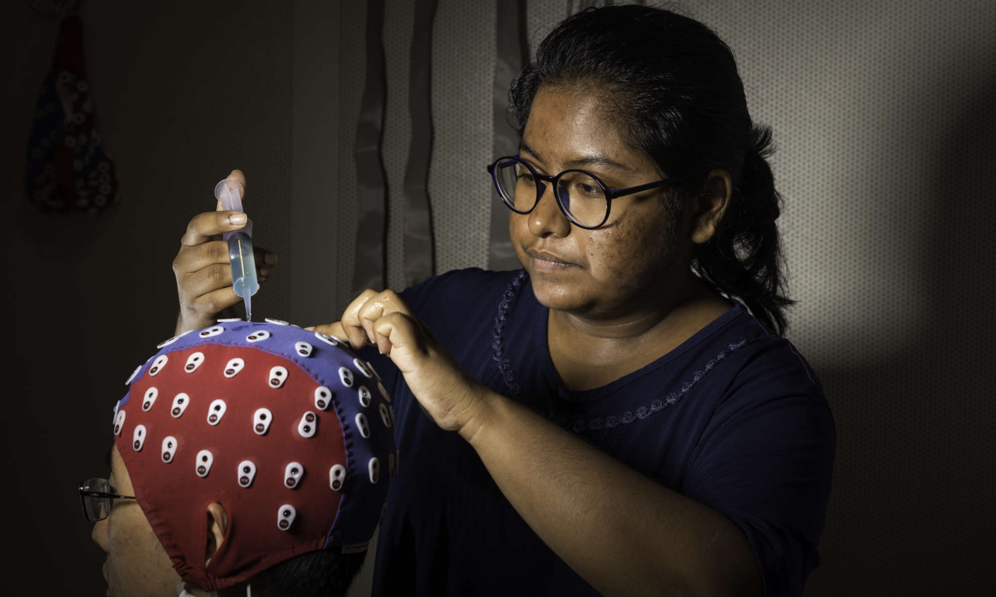 Biomedical engineering student adjusts an electroencephalography cap on a person