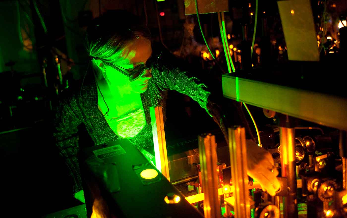 woman working in green glow of optical equipment