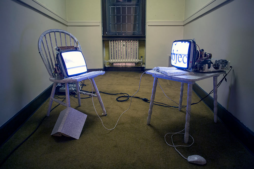 two chairs, carrying decopaged computer monitors and keyboards, facing each other