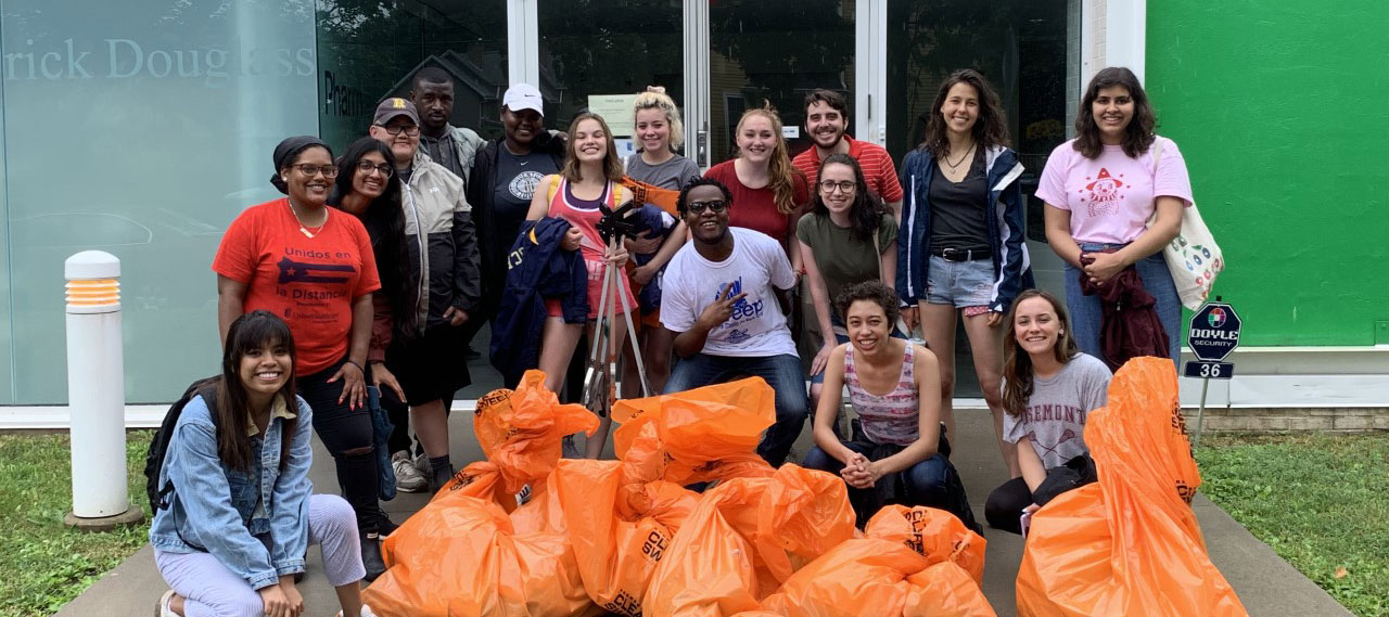 A group of student volunteers posing with their community clean up bags in front of the Frederick Douglass Building.
