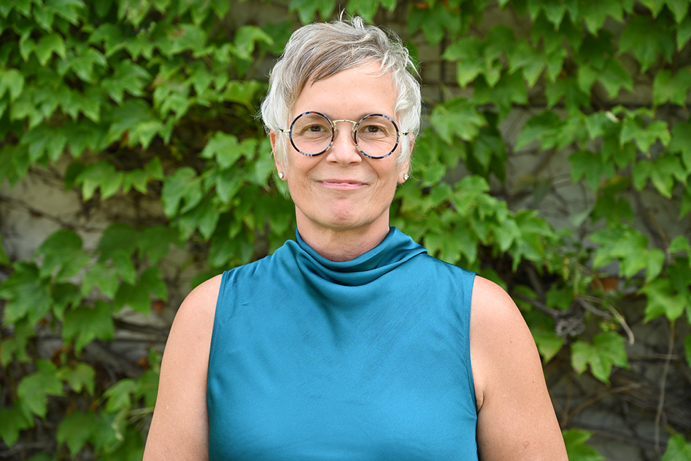 Dr. Beth Olivares stands in front of an ivy covered building.