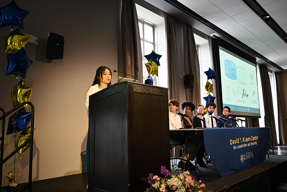 A student speaking to symposium attendees from behind a podium.