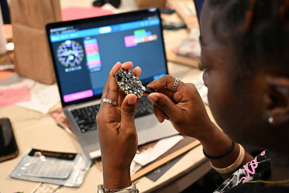 A student holds a CPX microcontroller.