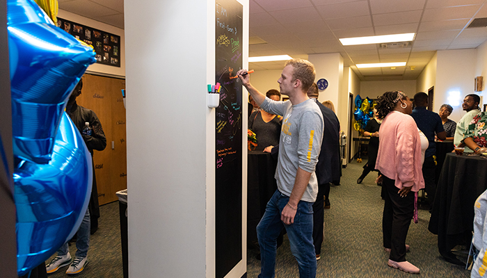 A few students writing messages on a welcome board.