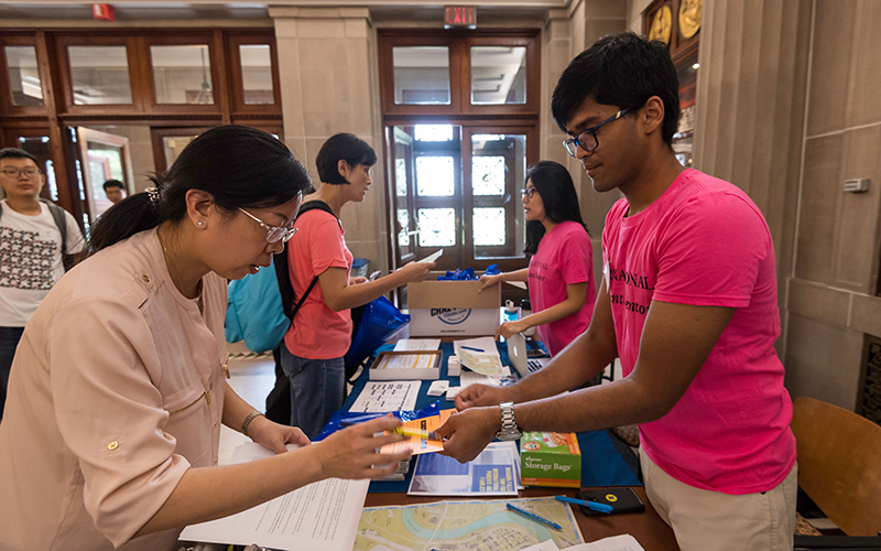 Photo of a student handing a card to a parent over a check-in table