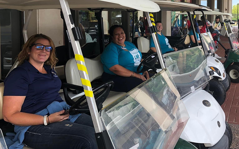 Photo of staff members and student volunteers seated on golf carts behind Rush Rhees Library during Fall Welcome Week