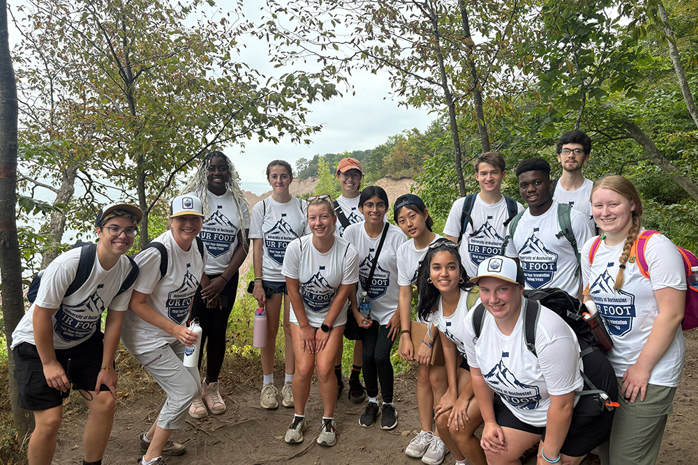 Students and University staff pose in front of a viewpoint at Chimney Bluffs State Park during a day trek