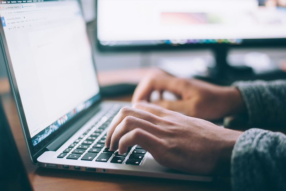 Hands hover over a laptop keyboard with the screen just out of focus
