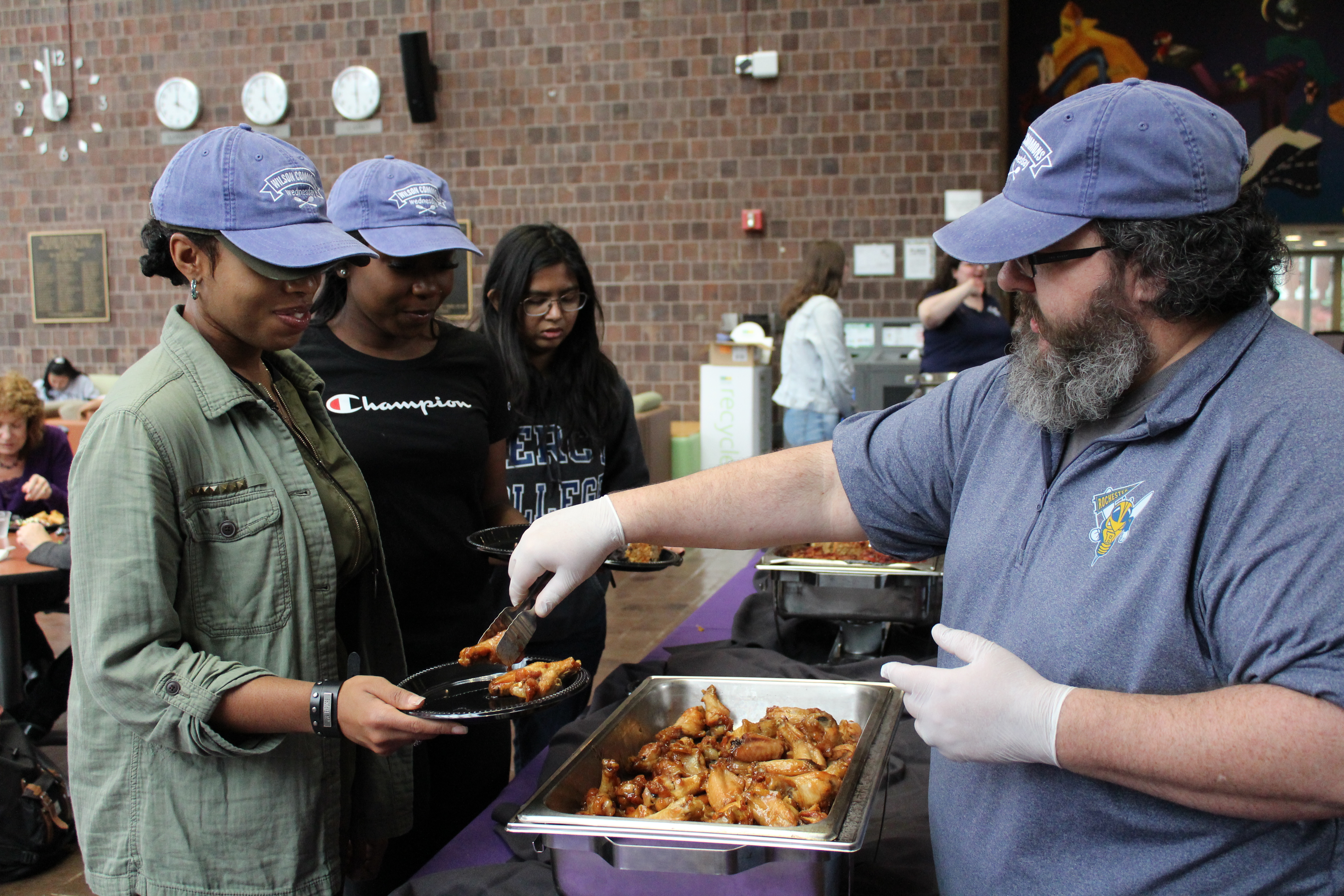 man serving two women food from a buffet tray