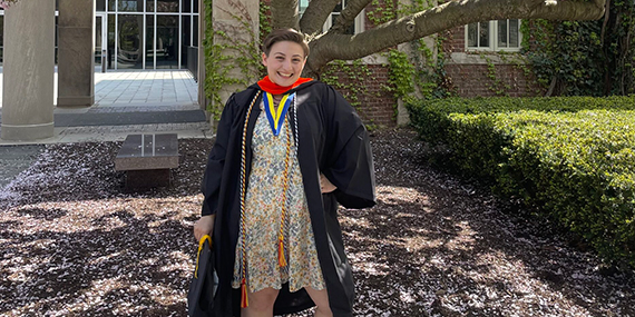 Adira Blumenthal poses outside while wearing her graduation gown.