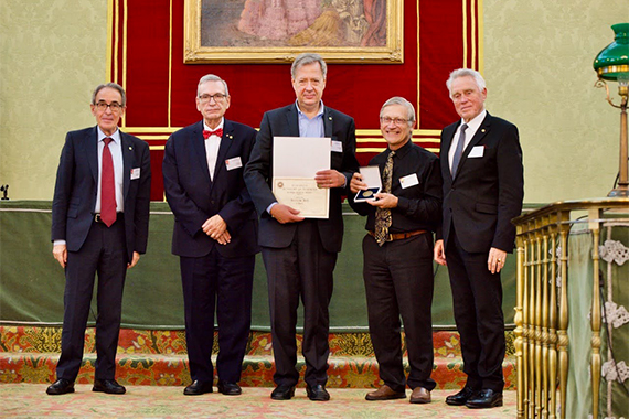 Five men, including Riccardo Betti in the center, pose on stage.