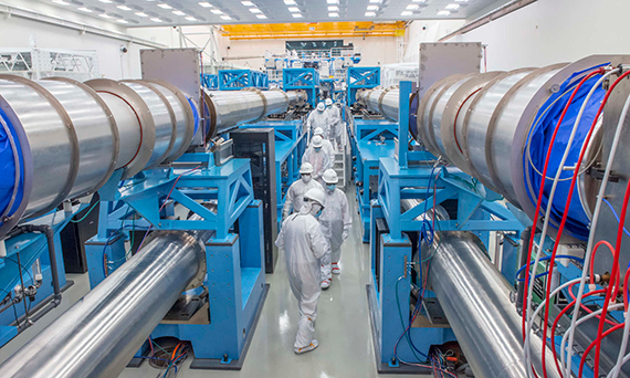 Laser Lab visitors and staff in white safety gear tour the OMEGA EP Target Bay.
