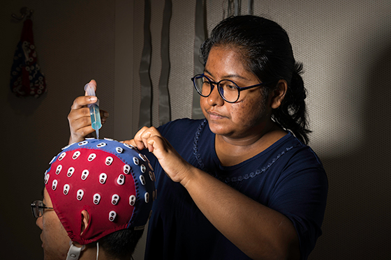 Biomedical engineering student adjusts an electroencephalography cap on a person.