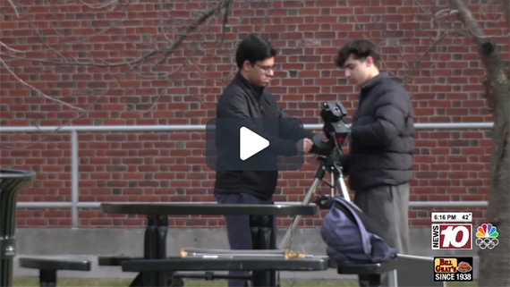 Asad Shahad and Adam Bowen stand outside adjusting a telescope.