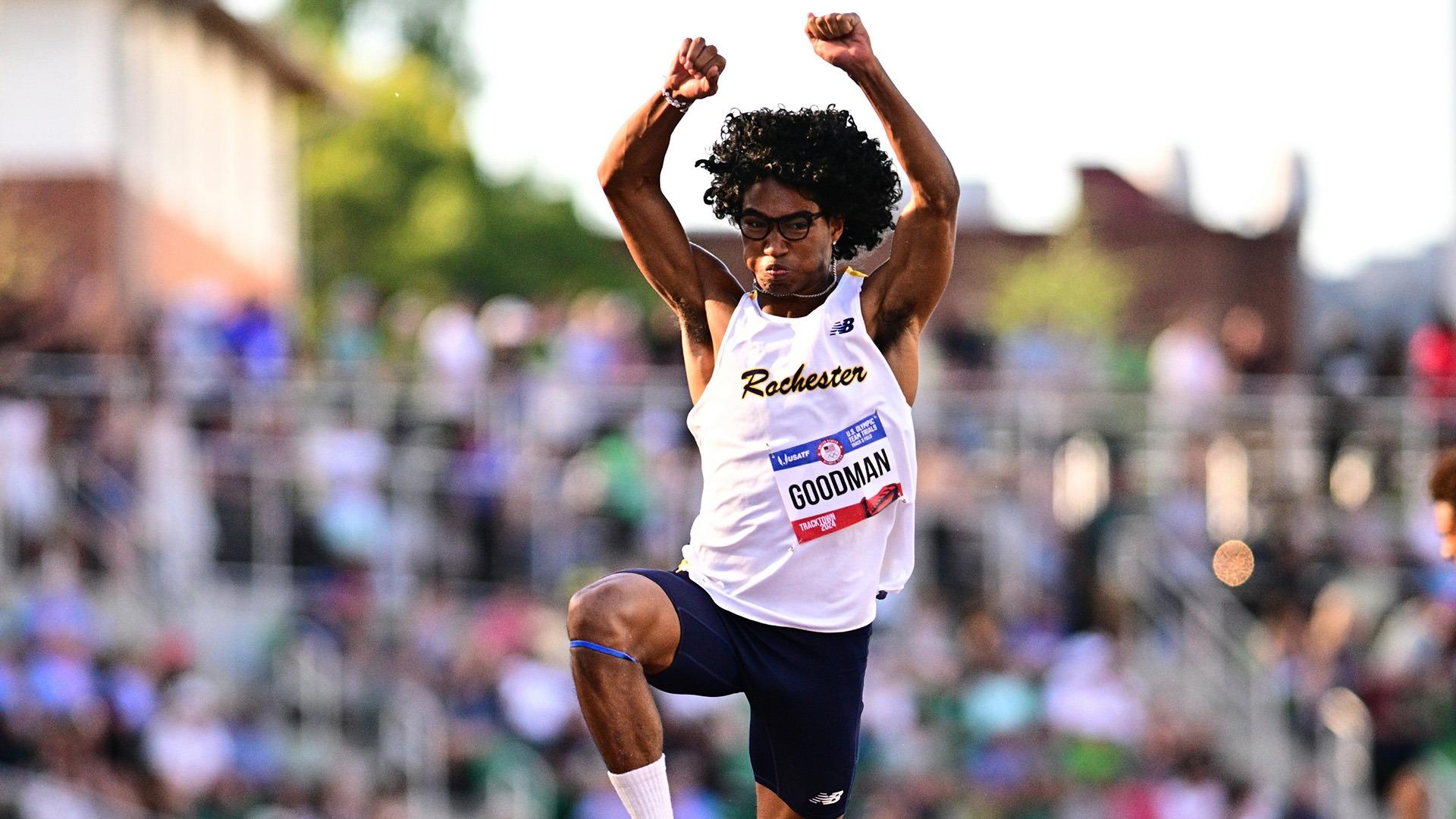 Cole Goodman leaps through the air in front of an outdoor crowd while performing the triple jump.