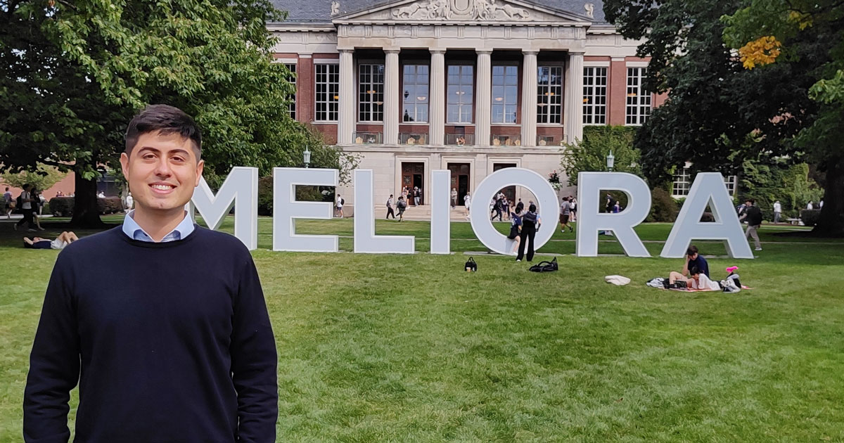 Alexis Sparapani poses for a photo on the University of Rochester campus in front of a display that reads: "Meliora".