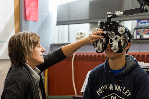 Optometrist Pat Weisenreder performs a vision screening on University of Rochester first year student and Handler scholar Michael Lin