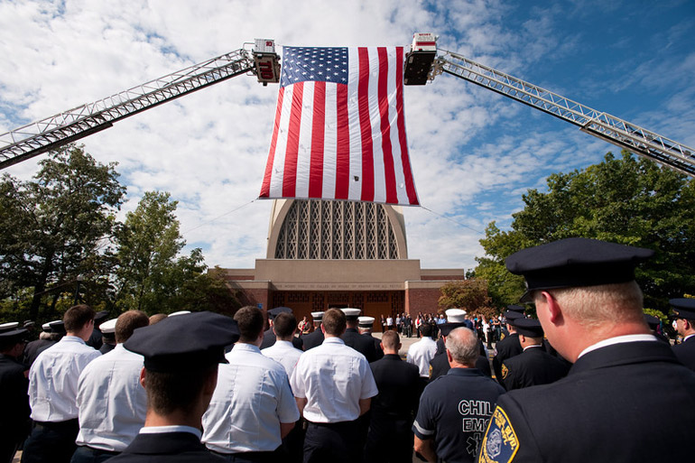 American flag hangs from crane in front of Chapel
