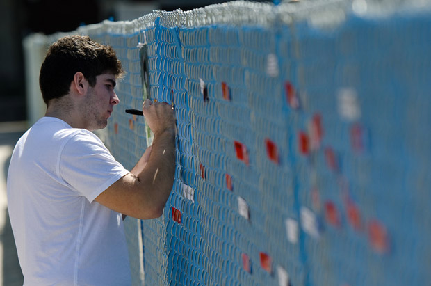student writes message on fence