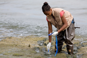 student testing water sample at lake