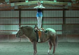 still from a film shows dancer standing on the back of a horse