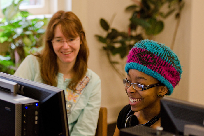 girl in colorful woven hat get help from librarian