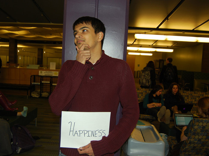student holding sign that reads HAPPINESS