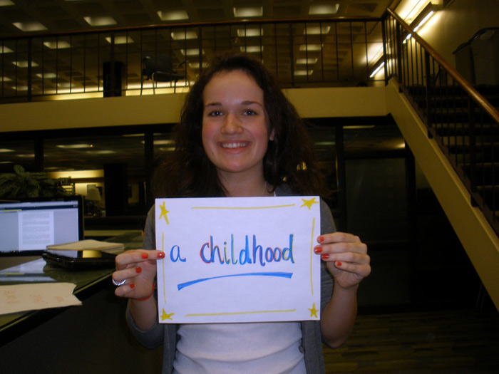 student holding sign that reads A CHILDHOOD