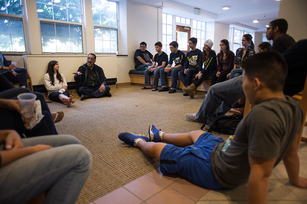 Paul Burgett sitting on the floor with a circle of students