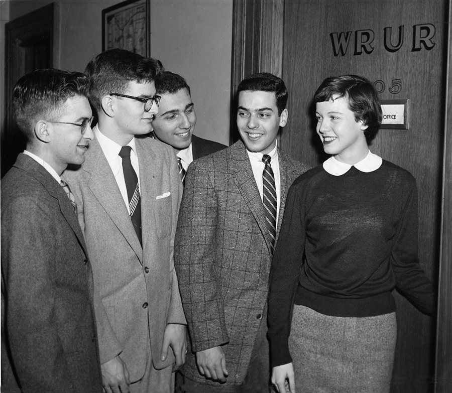 yearbook photo of a woman leading three men into the WRUR radio studio