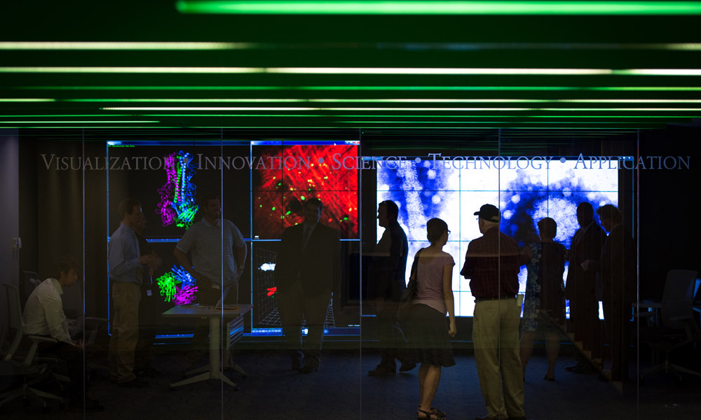 people walking in front of huge computer displays