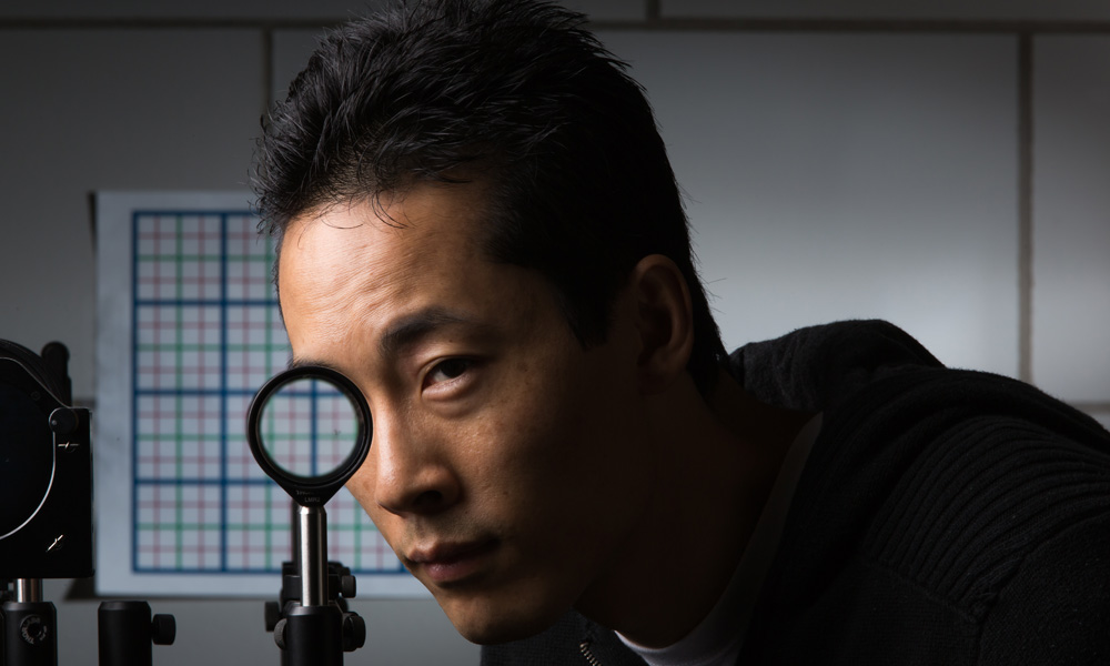 student place his face behind a round cloaking device and his eye appears to disappear