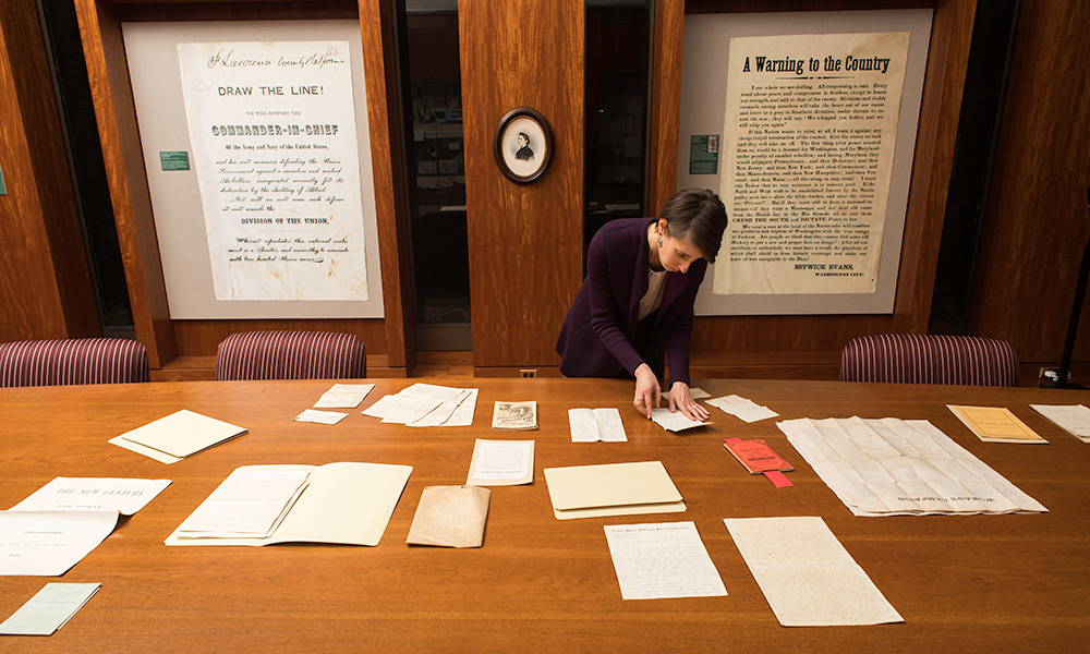 librarian looks at collection of letters on a table