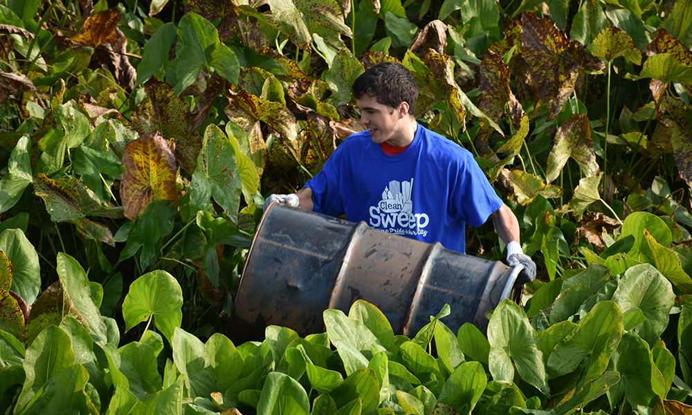 student carrying an oil drum out of the river