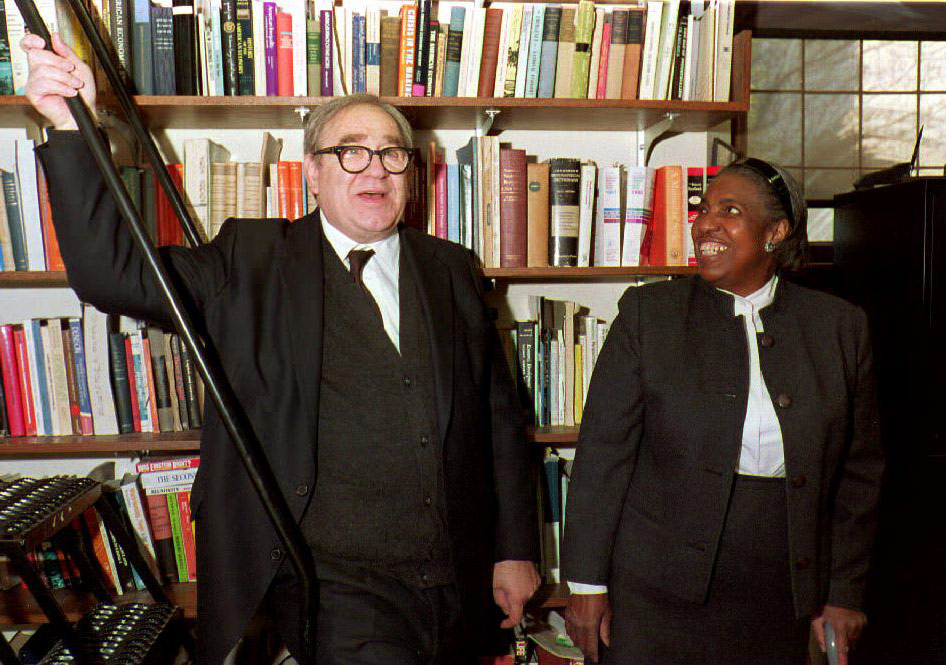 man and woman smiling in front of crowded bookcase