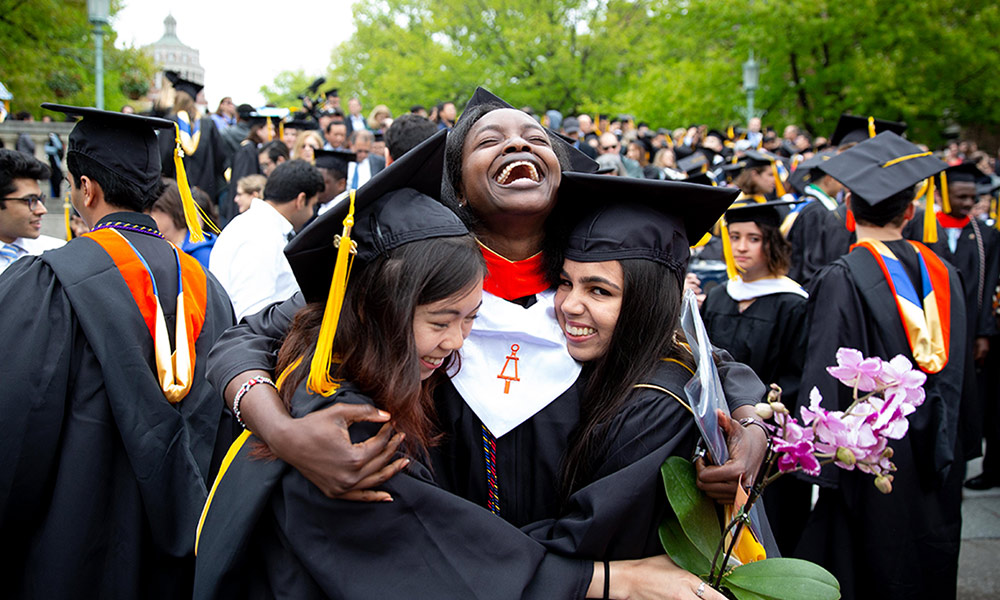 students laughing and hugging at commencement ceremony