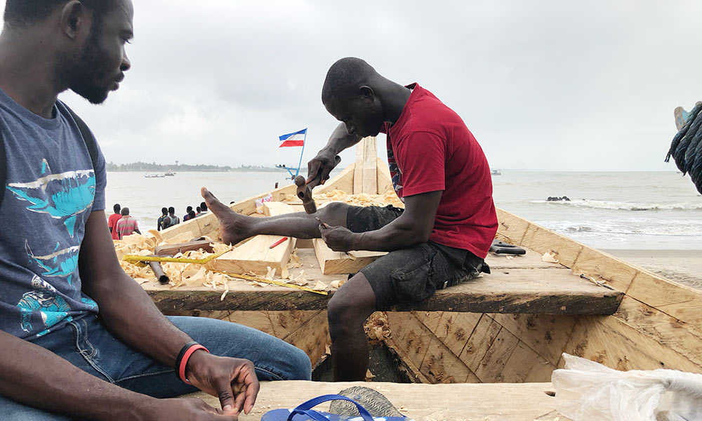 two men working on a wooden boat
