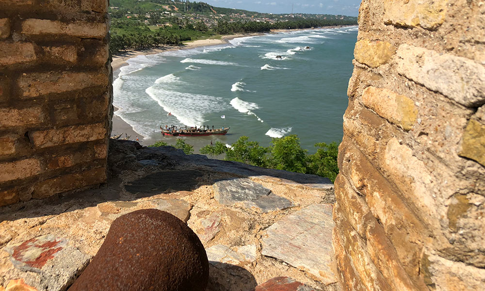 View of fishermen pushing a canoe into a bay in Elmina, from the cannon parapet of Fort Amsterdam