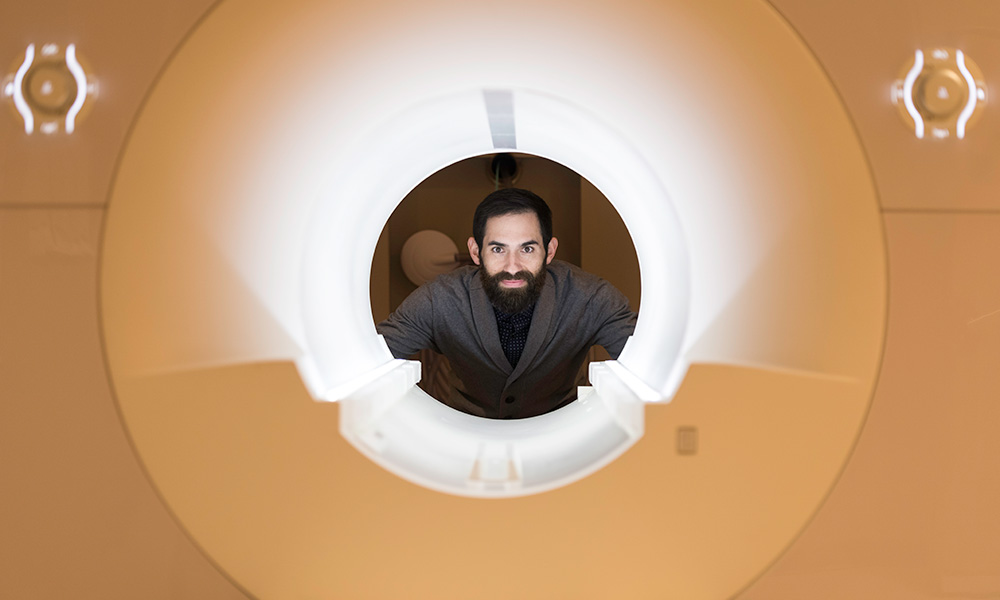 Photo of David Dodell-Feder behind fMRI machine