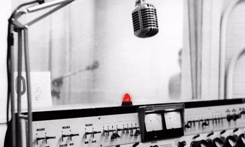 black and white image of a radio studio, with a red LIVE light