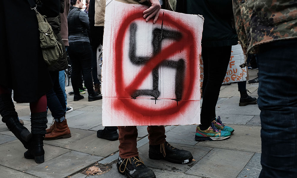 protester holding a sign with a swastika crossed out