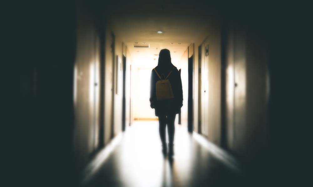 student walks down a dark school hallway