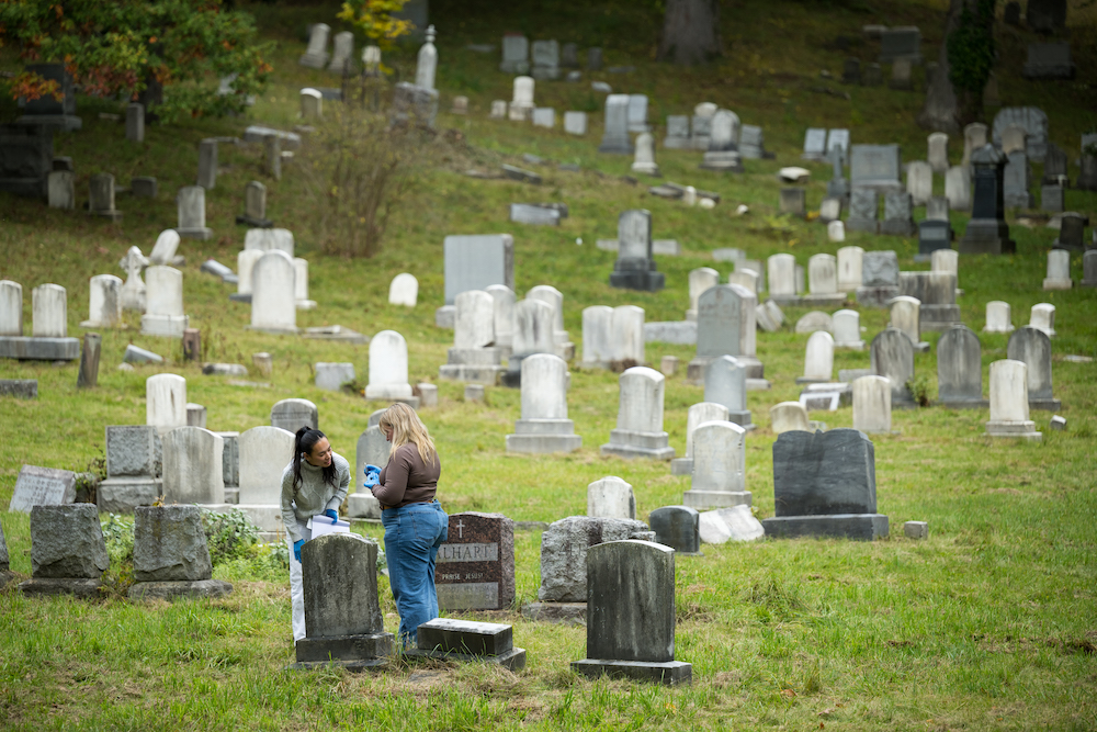 Two female college students in a cemetery studying beetles