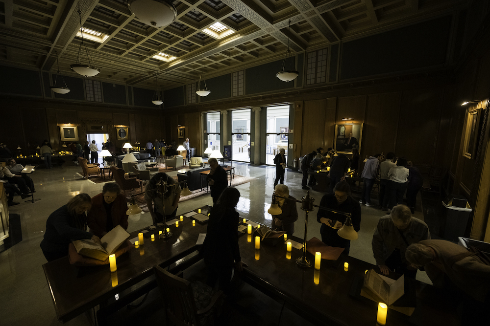 Visitors view pages of hand-written manuscripts spanning the Middle Ages from the collection of the Rossell Hope Robbins Library by electric candlelight