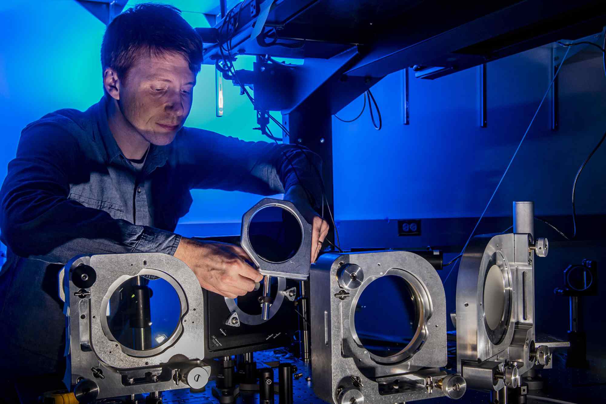 Jeremy Pigeon adjusts the parts of a laser system.