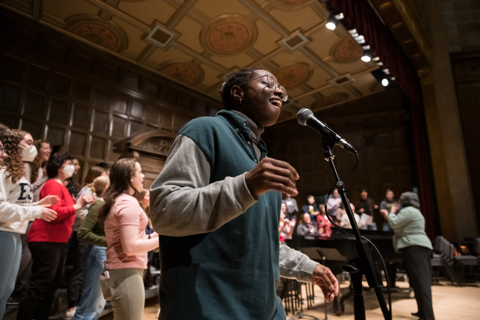 Singer steps up to microphone for a solo amid a choral rehearsal