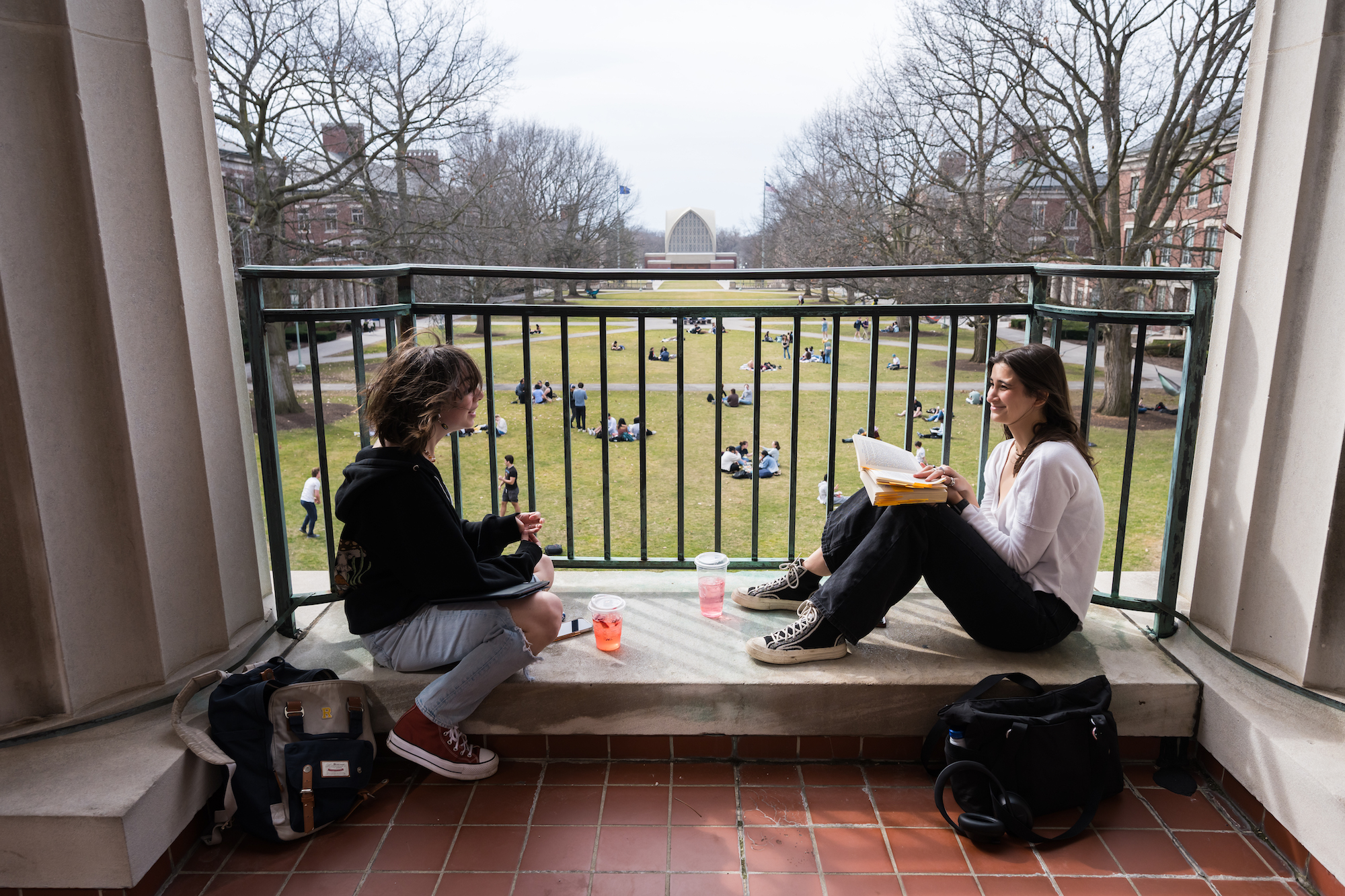 Students are seen on the Rush Rhees Library balcony overlooking University of Rochester’s Eastman Quad during a warm afternoon