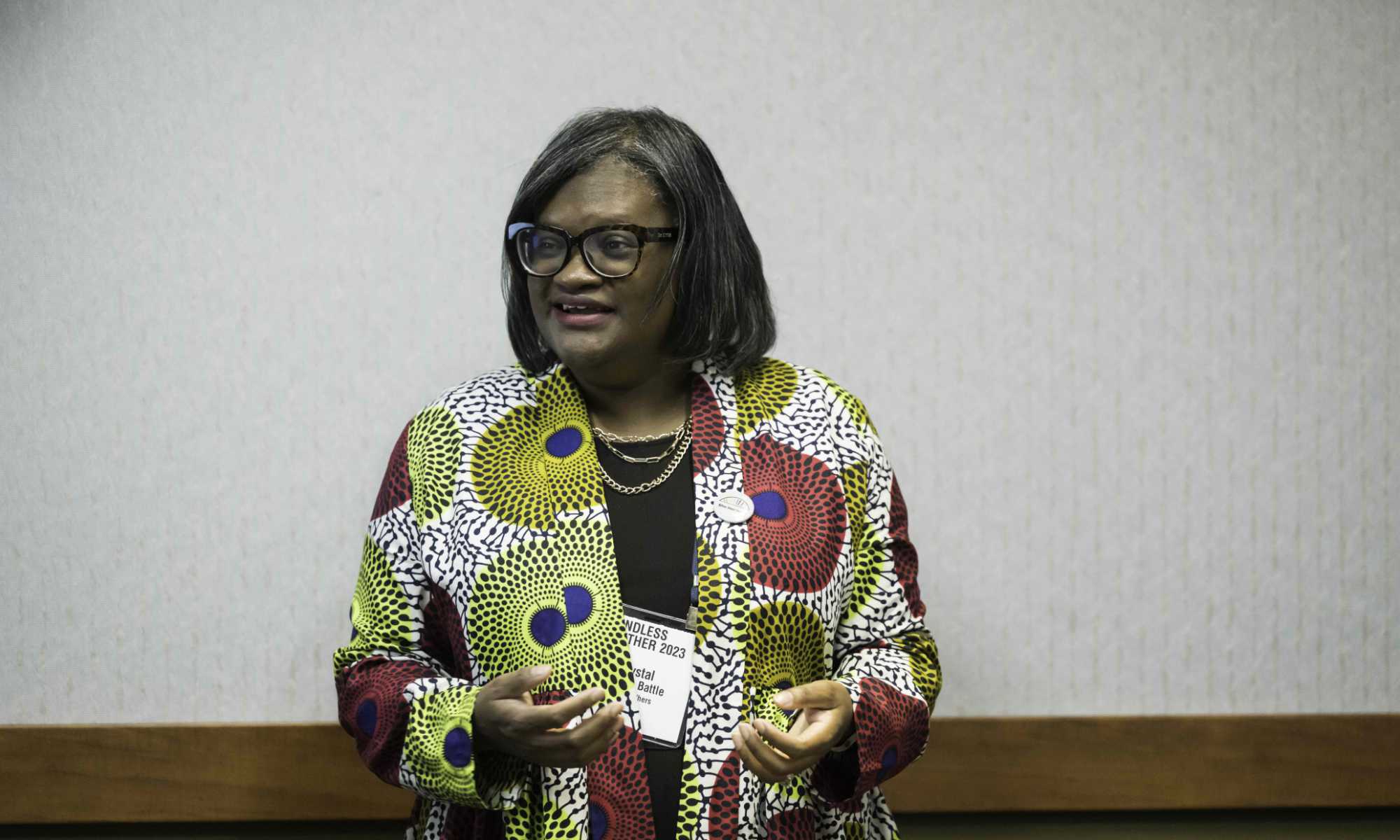 Crystal Sellers Battle speaking and gesturing in front of a room during a conference session. 