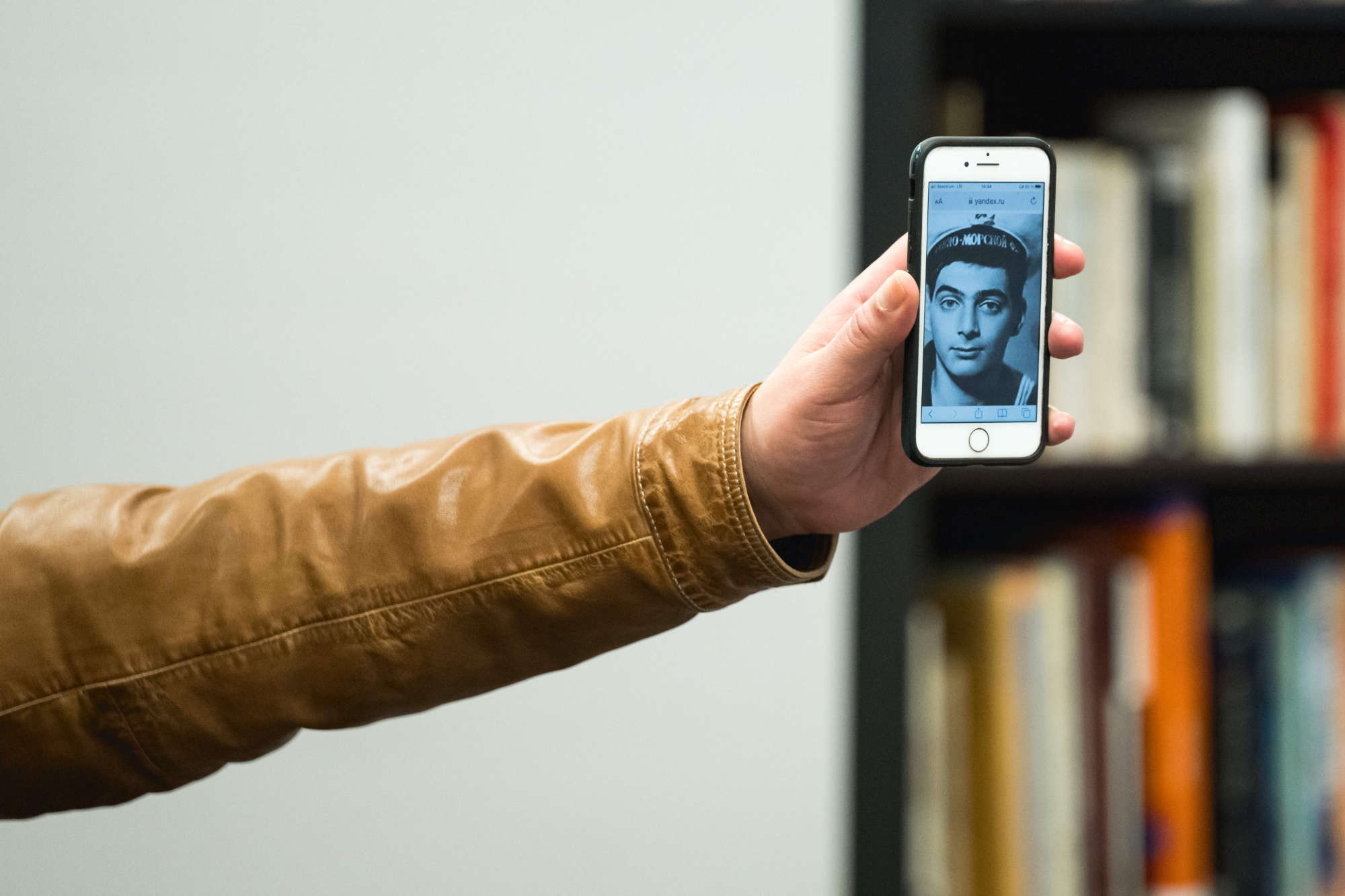 The arm of Dmitry Bykov displays a phone featuring a black and white photo of himself from his time in the Russian Army.