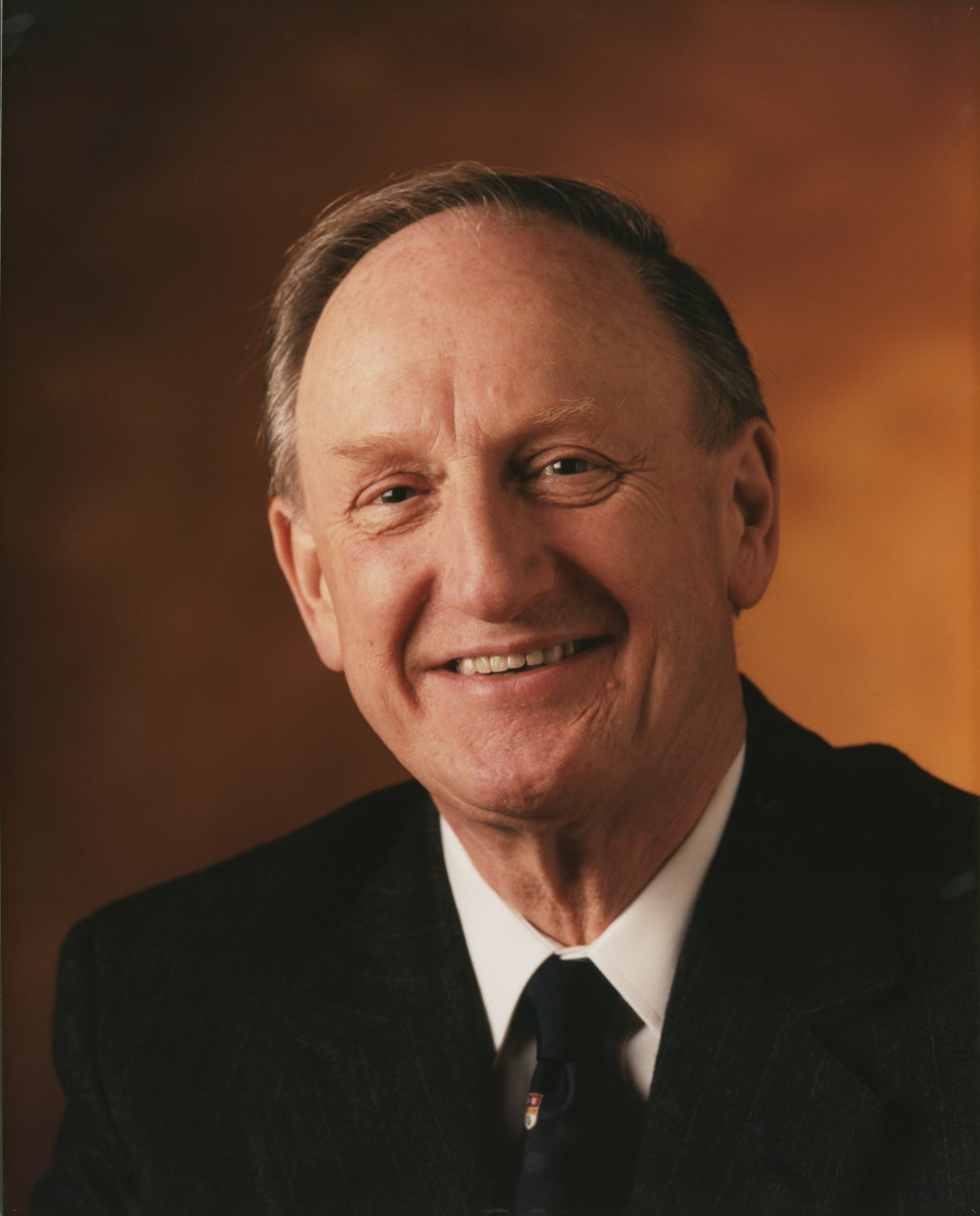 Headshot of Brian J. Thompson in a suit against a rust-colored background.
